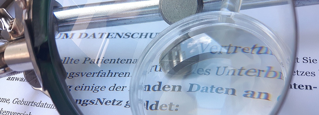 VertretungsNetz - Datenschutzbestimmung Foto: Lupe über einem Papier zum Datenschutz
