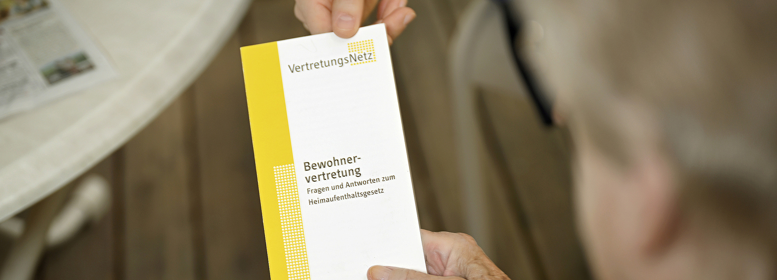 Vertretungsnetz Foto: Bewohnervertreterin übergibt einen VertretungsNetz-Folder an eine ältere Pflegeheimbewohnerin