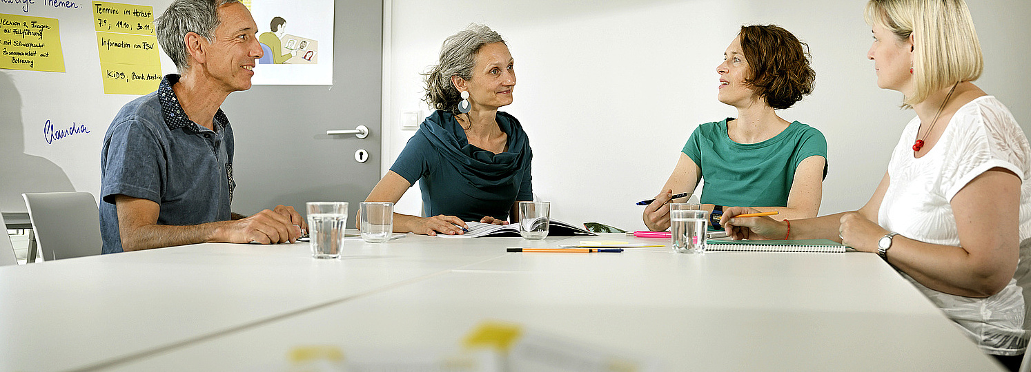 Arbeiten bei VertretungsNetz Foto einer Besprechung. Ein Mann und drei Frauen sitzen an einem Tisch