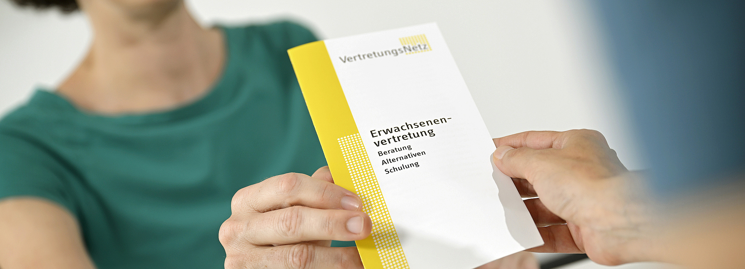 Erwachsenenvertretung Clearing Foto von einer Erwachsenenvertreterin, die einen Folder zum Thema Erwachsenenvertretung überreicht